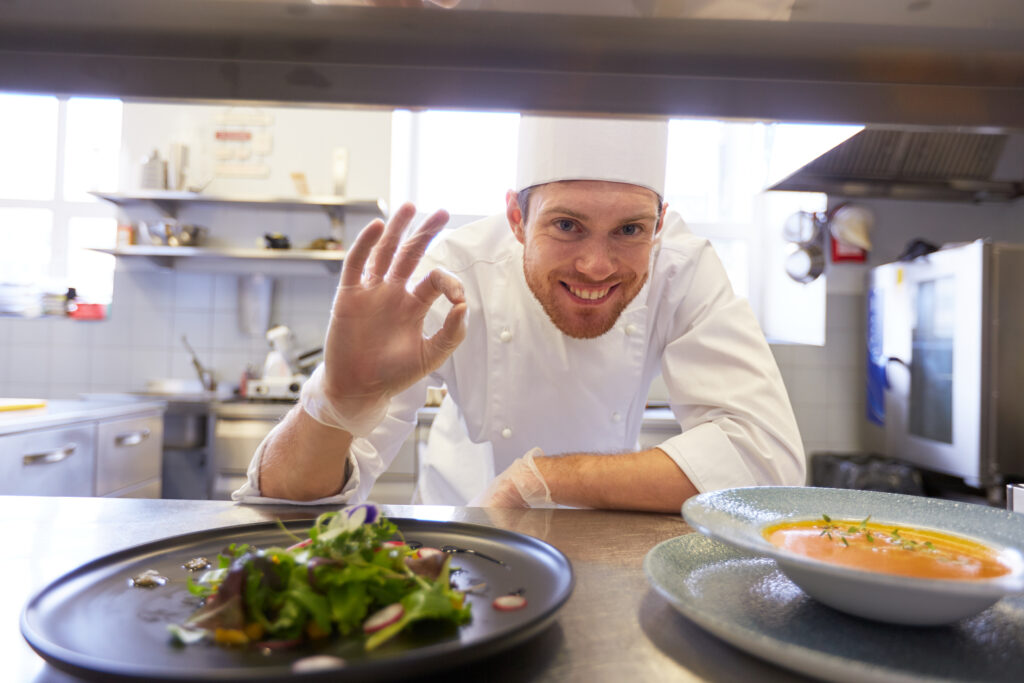happy male chef cooking food at restaurant kitchen